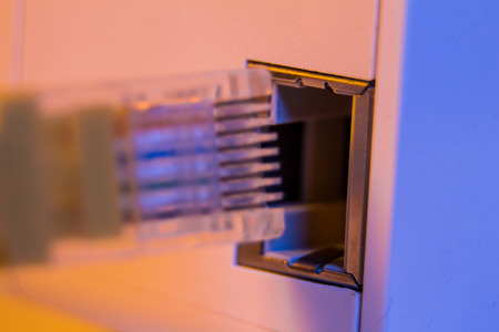 Macro close up of insert cable into WiFi extender device which is in electrical socket on the wall. The device is in access point mode that help to extend wireless network in home or office.の写真素材