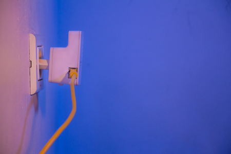 WiFi extender in electrical socket on the wall with cable plugged in. The device is in access point mode that help to extend wireless network in home or office.の写真素材