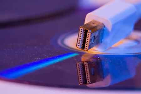 Closeup of white Mini Displayport cable with it's reflection on blank disc.の写真素材