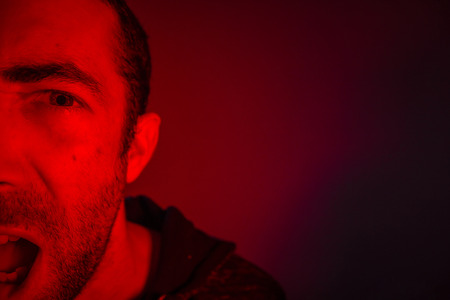 Man with angry facial expression screaming out loud. Close up portrait of a man shouting with mouth wide open.の写真素材