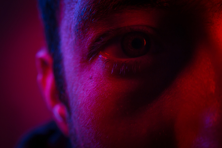 Close up on man face with mysterious facial expression. Portrait of suspicious young man.の写真素材