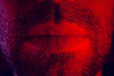 Macro close up on man mouth with serious facial expression. Portrait of expressionless young man.の写真素材