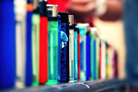 Lighters lined up. One blue color lighter stands out from the rest. Man's face Illustrated on it and it looks like he glances out to the camera. Closeup, selective focus with copy space.の写真素材