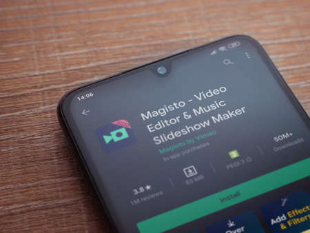 Lod, Israel - July 8, 2020: Magisto - Video Editor and Movie Maker app play store page on the display of a black mobile smartphone on wooden background. Top view flat lay with copy space.のeditorial素材