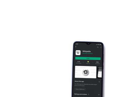 Lod, Israel - July 8, 2020: Wikipedia app play store page on the display of a black mobile smartphone isolated on white background. Top view flat lay with copy space.のeditorial素材