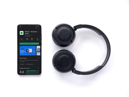 Lod, Israel - July 8, 2020: Black mobile smartphone with Blinkist app play store page and wireless headphones on a white background. Top view flat lay with copy space.のeditorial素材