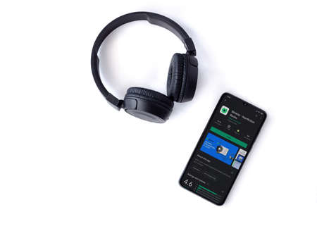 Lod, Israel - July 8, 2020: Black mobile smartphone with Blinkist app play store page and wireless headphones on a white background. Top view flat lay with copy space.のeditorial素材