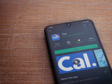 Lod, Israel - July 8, 2020: Cal app play store page on the display of a black mobile smartphone on wooden background. Top view flat lay with copy space.のeditorial素材