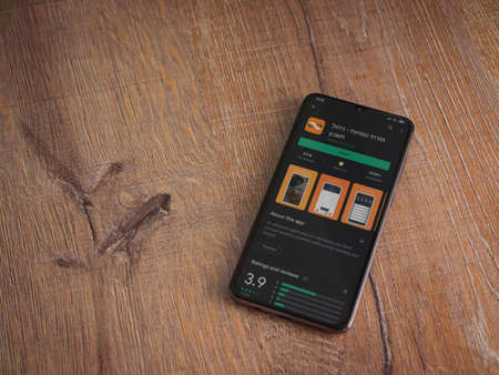 Lod, Israel - July 8, 2020: Bank Mizrahi Tefahot app play store page on the display of a black mobile smartphone on wooden background. Top view flat lay with copy space.のeditorial素材