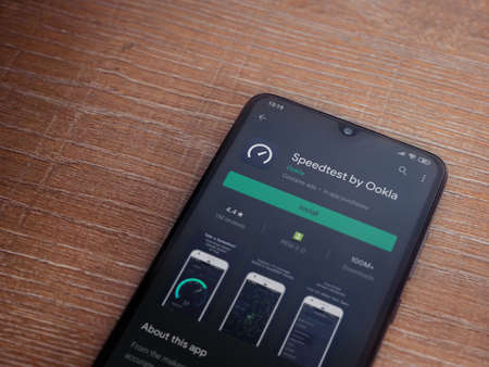 Lod, Israel - July 8, 2020: Speedtest app play store page on the display of a black mobile smartphone on wooden background. Top view flat lay with copy space.のeditorial素材