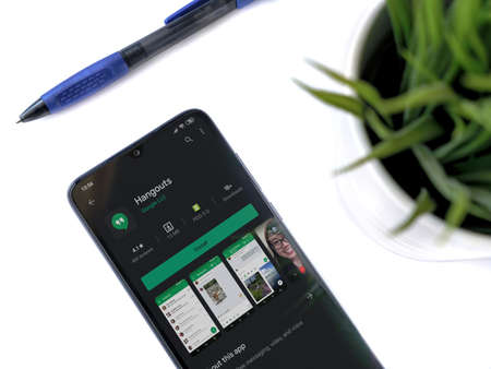 Lod, Israel - July 8, 2020: Modern minimalist office workspace with black mobile smartphone with Eyecon app play store page on white background. Top view flat lay with copy space.のeditorial素材