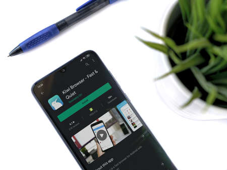 Lod, Israel - July 8, 2020: Modern minimalist office workspace with black mobile smartphone with Kiwi Browser app play store page on white background. Top view flat lay with copy space.のeditorial素材
