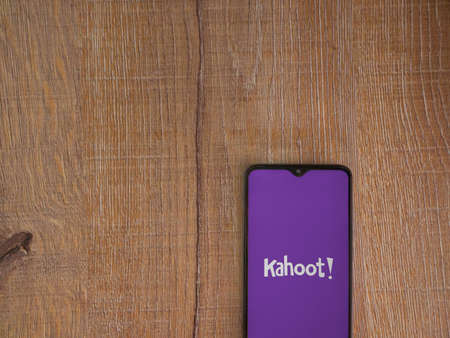 Lod, Israel - July 8, 2020: Kahoot! app launch screen with logo on the display of a black mobile smartphone on wooden background. Top view flat lay with copy space.のeditorial素材