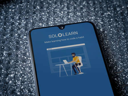 Lod, Israel - July 8, 2020: SoloLearn - Learning coding app launch screen with logo on the display of a black mobile smartphone on a metallic background. Close up top view flat lay.のeditorial素材