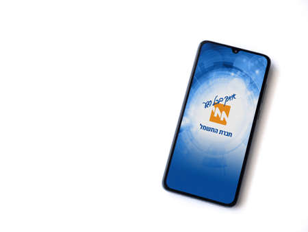 Lod, Israel - July 8, 2020: Israel Electric Corporation app launch screen with logo in hebrew text on the display of a black mobile smartphone isolated on white background. Top view flat lay with copy space.のeditorial素材