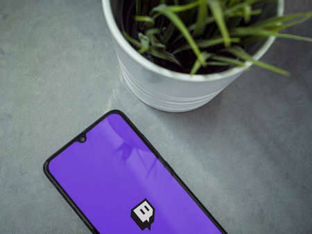 Lod, Israel - July 8, 2020: Modern minimalist office workspace with black mobile smartphone with Twitch app launch screen with logo on a marble background. Close up top view flat lay.のeditorial素材