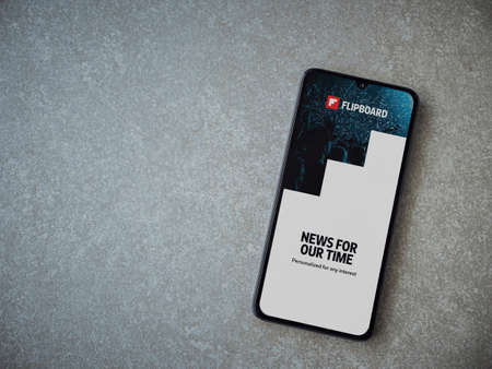 Lod, Israel - July 8, 2020: Flipboard app launch screen with logo on the display of a black mobile smartphone on ceramic stone background. Top view flat lay with copy space.のeditorial素材