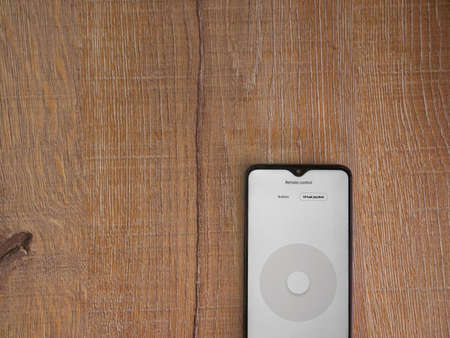 Lod, Israel - July 8, 2020: Roborock app launch screen with logo on the display of a black mobile smartphone on wooden background. Top view flat lay with copy space.のeditorial素材