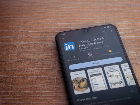 Foto de Lod, Israel - July 16,2023: LinkedIn app play store page on smartphone on wooden background. Top view flat lay with copy space. - Imagen libre de derechos