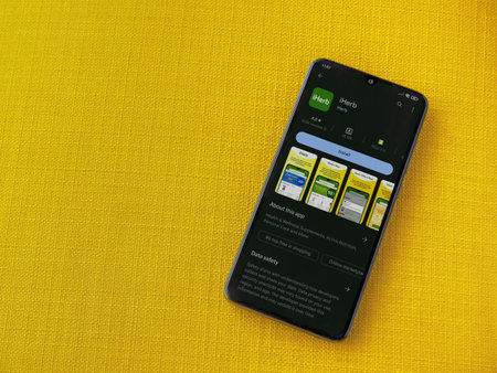 Lod, Israel - July 16,2023: iHerb app play store page on smartphone on a yellow fabric background. Top view flat lay with copy space.のeditorial素材
