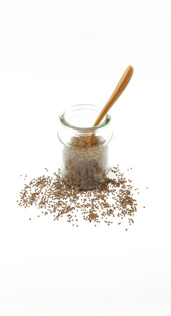 Perila seed in glass jar with wooden spoon on a white backgroundの写真素材