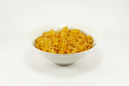 Bowl of cornflakes on colorful table mat; white background