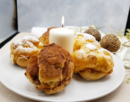 Chocolate and vanilla choux cream puff with candle on white plate