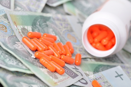 pile of orange pills on banknotesの写真素材
