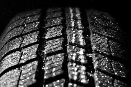 Winter car tire in rain, dark backgroundの写真素材