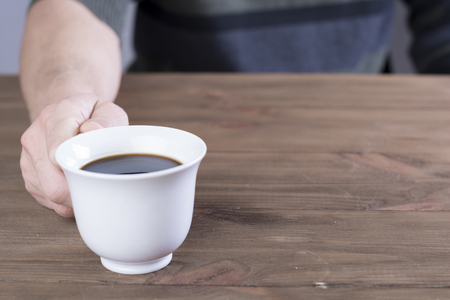 Man holding coffee on old wooden tableの写真素材