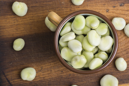 Fresh broad beans in bowl on wooden boardの写真素材
