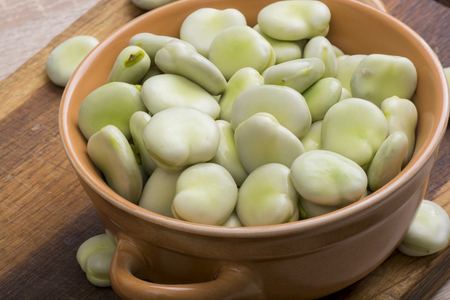 Fresh broad beans in bowl on wooden boardの写真素材