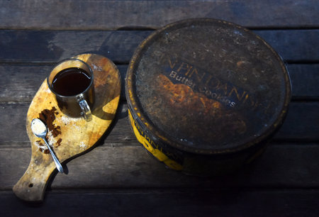 BALI,INDONESIA-JULY 22,2021: A cup of coffee with an old rusty empty box of PinPin Dan biscuitのeditorial素材