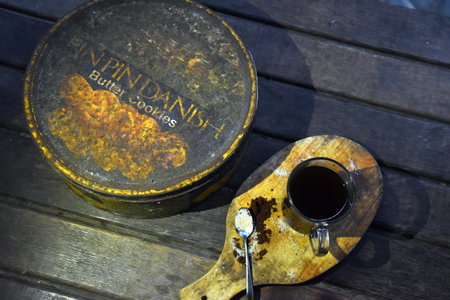 BALI,INDONESIA-JULY 22,2021: A cup of coffee with an old rusty empty box of PinPin Dan biscuitのeditorial素材
