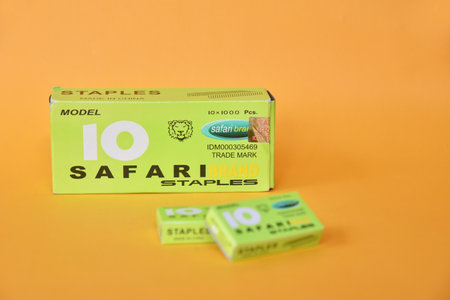 BALI,INDONESIA-AUGUST 09 2021: Staples in green box isolated on yellow background