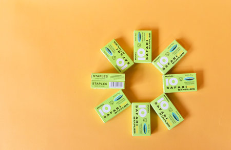 BALI,INDONESIA-AUGUST 09 2021: Staples in green box isolated on yellow background