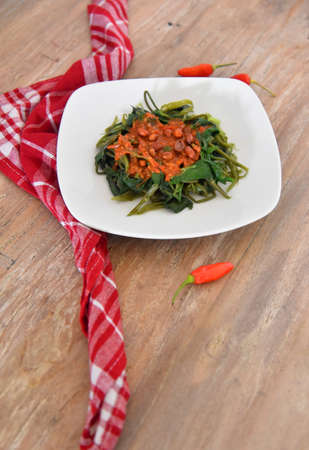 Water spinach vegetable names in Indonesian language"Plecing Kangkung",placed on the brown wooden tableの写真素材