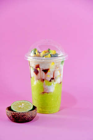 Avocado drink mix with fresh milk  served on plastic glass,two layers looks,isolated on color...