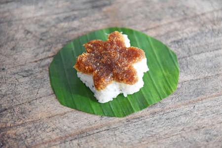 Traditional indonesian rice cake in star form,with coconut palm sugar sauce,served with banana leafs on brown wooden tableの写真素材