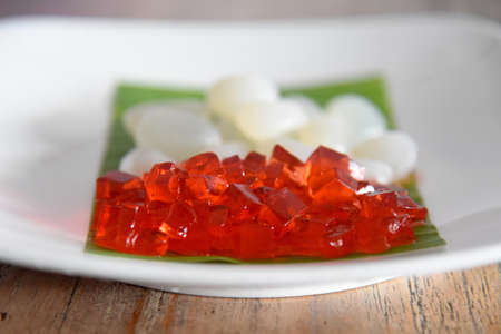 Red jelly and white palm fruit (KOLANG KALING),placed on white plate on brown wooden background