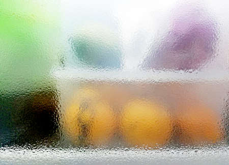 Water dew on the fridge's window,with some blurred fruits background