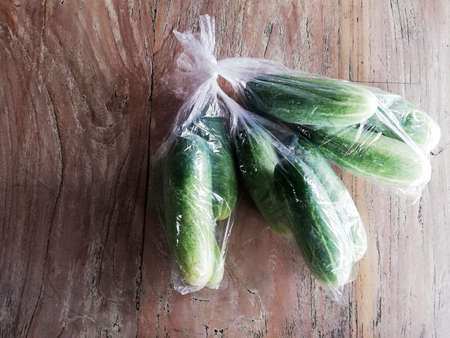 Cucumbers packed on platic bag,placed on brown wooden backgroundの写真素材