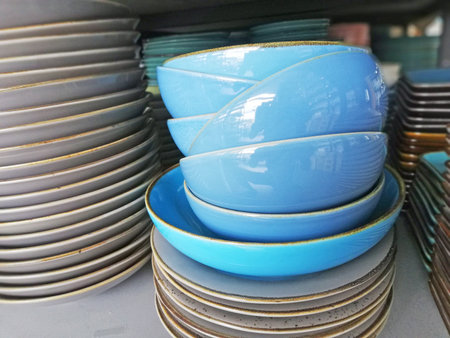 Colorful ceramic plates and bowls stacked in a shop window, close-upの写真素材