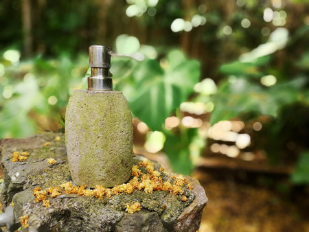 Liquid soap dispenser on a stone in the garden with nature backgroundの写真素材