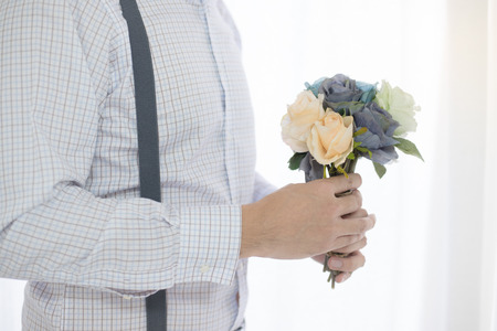 Close up man holding flower bouquet by windowの写真素材