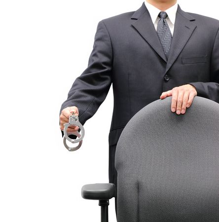 Business man standing behind an office chair holding a pair of handcuffs, isolated on a white background.の写真素材