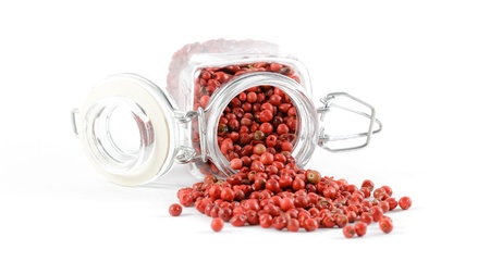 Pink peppercorns spilling out of its spice jar, isolated on a white background. の写真素材