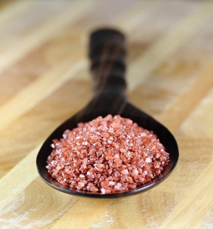 Red Hawaiian sea salt in a wooden spoon on a wooden table.の写真素材
