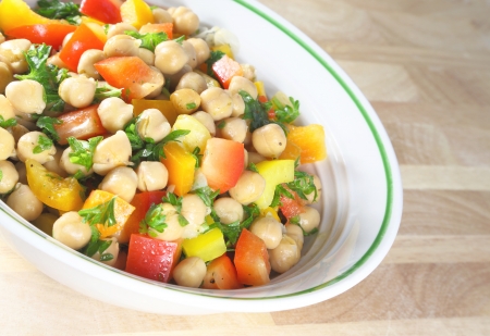 Chick pea salad in a bowl sitting on a wooden table.の写真素材