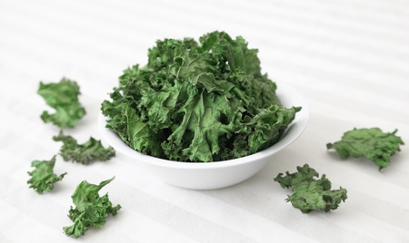 A bowl of home-made kale chips sitting on a table.の写真素材